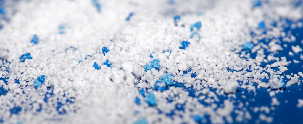 Microscopic view of various microplastic particles in different shapes and colors, scattered on a surface.