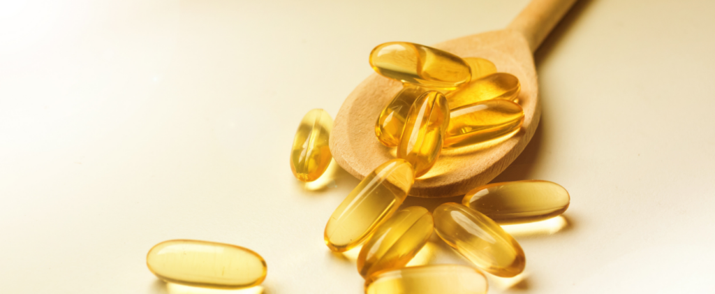 An open bottle of omega-3 capsules spilled on a table.