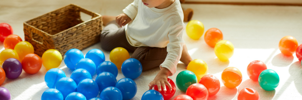 Child sitting on the floor playing with plastic toy balls.